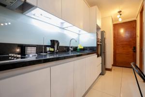 a kitchen with white cabinets and a black counter top at Delightful Studio Apartment in Las Condes in Santiago +33 photos