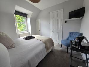 a bedroom with a bed and a blue chair at Tullochard Guest House in Alness