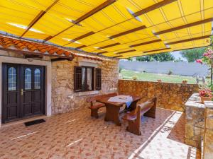 patio ze stołem i ławkami pod żółtym parasolem w obiekcie Holiday Home Laura by Interhome w Puli