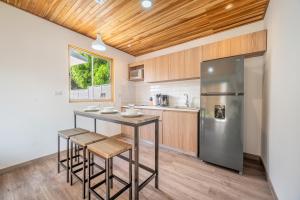 a kitchen with a island with stools and a refrigerator at Macondo Ecolodge Apt 5 - Alpinias in Coco