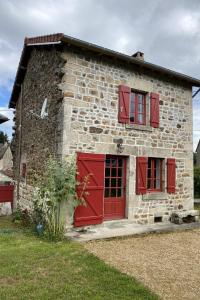 a stone house with red doors and windows at Gîte les hortensias in Saint-Moreil