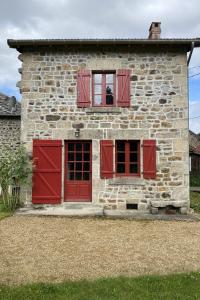 a stone house with red doors and windows at Gîte les hortensias in Saint-Moreil