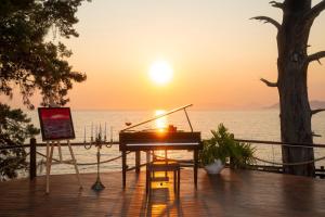 a piano sitting on a deck with the sunset in the background at Lov Faralya Adults Only in Faralya