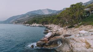 a group of people sitting on a cliff next to the water at Lov Faralya Adults Only in Faralya