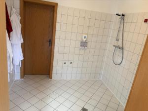 a white tiled bathroom with a shower and a door at Ihr Kuschelnest in Wathlingen +11 photos