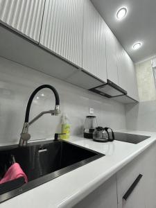 eine Küche mit einer schwarzen Spüle und weißen Schränken in der Unterkunft город Балхаш, Шашубая 8г in Zhezdi