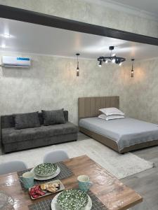 ein Schlafzimmer mit einem Bett, einem Tisch und einer Couch in der Unterkunft город Балхаш, Шашубая 8г in Zhezdi + 17 Fotos