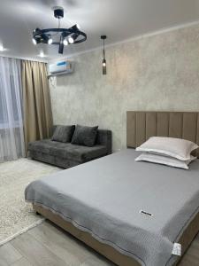 ein Schlafzimmer mit einem großen Bett und einer Couch in der Unterkunft город Балхаш, Шашубая 8г in Zhezdi