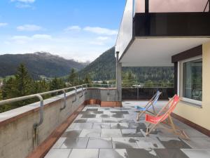 two chairs on a balcony with mountains in the background at Apartment Allod Park Haus C 701 by Interhome in Davos
