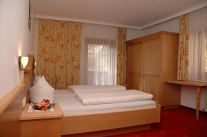 a small bedroom with a bed and a window at Hotel-Garni Almhof in Mayrhofen