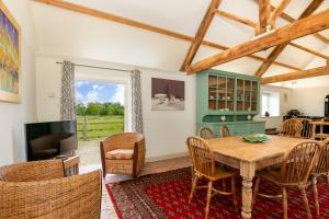 a dining room with a wooden table and a tv at Priory Courtyard - 3 Bedroom Countryside Escape 