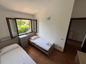 a small room with two beds and a window at La Terrazza Sa Cruxitta in Portoscuso