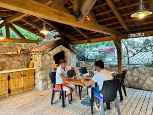 a group of people sitting at a table on a patio at Pljesa Apartments -Meerblick mit Terrasse & Grill by rentyourhome24 in Supetarska Draga