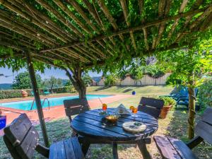 a table and chairs under a pergola next to a pool at Apartment Fienile by Interhome in Sasso Pisano