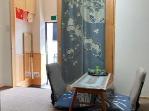 einen Tisch und Stühle in einem Zimmer mit einem Tisch und einem Vorhang in der Unterkunft 吉祥民宿 in Kyoto