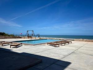 a swimming pool with a slide and benches next to the ocean at Tazgha house in Essaouira