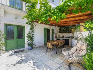 a patio with a table and chairs and a green door at Holiday Home Villa Radovani by Interhome in Višnjan