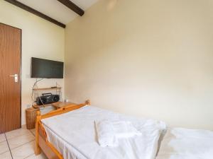 een slaapkamer met een bed met witte lakens en een televisie bij Apartment Am Hohen Bogen-11 by Interhome in Arrach