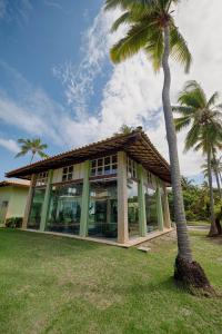 a building with a palm tree in front of it at RESERVA IMBASSAI - APARTAMENTO TD 17 202 BUGANVILIAS in Imbassai