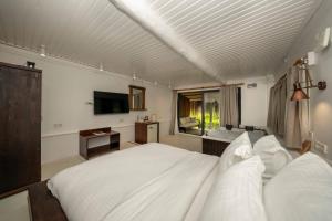 a bedroom with a large white bed and a television at Lov Faralya Adults Only in Faralya