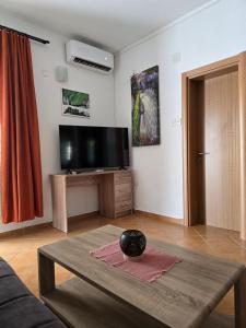 a living room with a table and a flat screen tv at Kostic Apartments in Buljarica