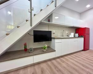 a kitchen with white cabinets and a tv under a staircase at Cosy Paradise in Palouki