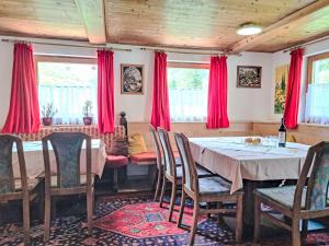a dining room with a table and red curtains at Holiday Home Farm Eben by Interhome in Ginzling