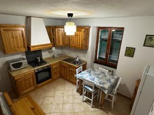 a kitchen with wooden cabinets and a table with chairs at CA'da LU' in Velva +18 photos