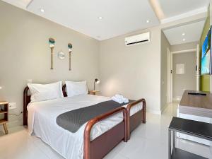 a bedroom with a bed and a desk in a room at Piscina - 200m do mar - AC - 1 Suite com banheiro in Guarujá
