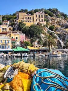 a boat in a body of water with buildings at Lirenou Scala Vista in Symi