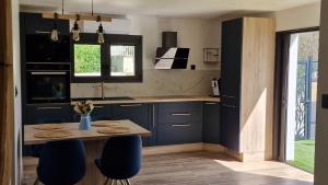 a kitchen with blue cabinets and a table and chairs at LE MUGEL cocooning SPA et proche calanques de Cassis in Carnoux