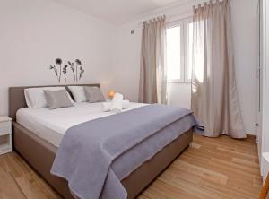 a white bedroom with a large bed and a window at Apartments Villa Senija in Prizba