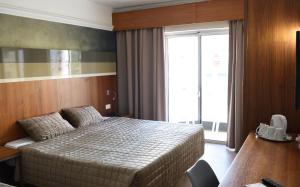 a hotel room with a bed and a desk and a window at Topaz Hotel in St Paul's Bay