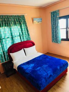 a bedroom with a bed with a blue blanket and a window at Hagounia hotel in Tan-Tan Plage
