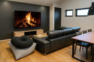 a living room with a leather couch and a fireplace at Fuji Sauna Club サウナ 露天風呂 新築一棟貸し アウトレット スピードウェイすぐ in Sukawa
