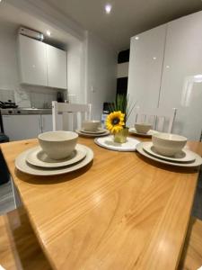 una mesa de madera con cuencos y platos en la cocina en Apartment in the heart of London, en Moffat