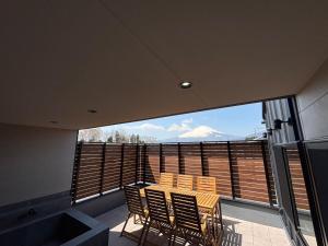 a balcony with a table and chairs and a large window at Fuji Sauna Club サウナ 露天風呂 新築一棟貸し アウトレット スピードウェイすぐ in Sukawa