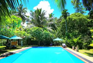 a swimming pool with palm trees in the background at Shangri-lanka Villa in Bentota