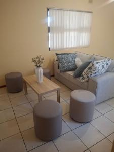 a living room with a couch and two stools and a table at Fundisa's Place in Port Shepstone +1 photo