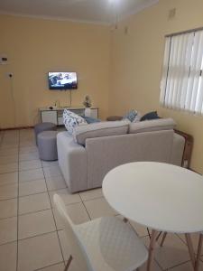 a living room with a couch and a table and a tv at Fundisa's Place in Port Shepstone