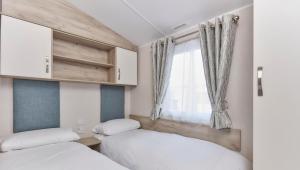 two beds in a small room with a window at Ruda Holiday Park in Croyde +75 photos