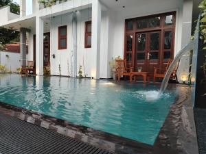 a swimming pool with a fountain in front of a house at Villa White Elephant in Hikkaduwa