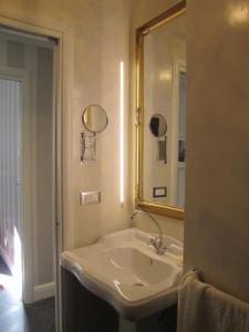 a white bathroom with a sink and a mirror at La Finestra Sul Cortile in Aosta
