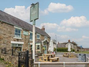 eine Gruppe Picknicktische vor einem Gebäude in der Unterkunft Cosy Cottage 4 in Durham