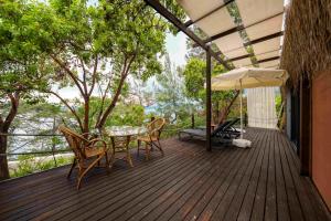 a wooden deck with a table and chairs and an umbrella at Lov Faralya Adults Only in Faralya