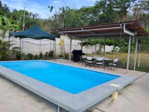 a swimming pool in a backyard with a grill and a table and chairs at Centro Vacacional el Amanecer in Puntarenas