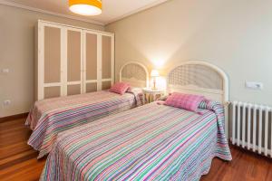 two beds with striped sheets in a room at Apartamentos Cotiello in Llanes
