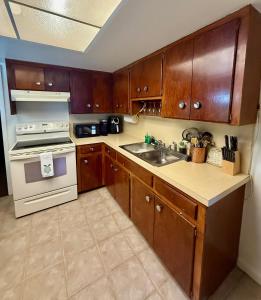 a kitchen with wooden cabinets and a stove and a sink at Riviera Haven, 10 Minutes from the Beach, Coastal Town, Quaint & Comfy in Riviera Beach