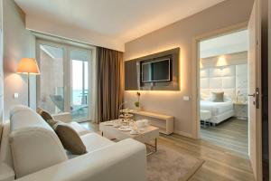 a living room with a white couch and a bedroom at Almar Jesolo Resort & Spa in Lido di Jesolo