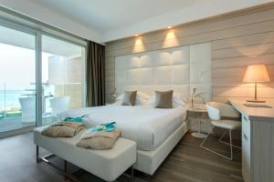 a bedroom with a large white bed and a desk at Almar Jesolo Resort & Spa in Lido di Jesolo